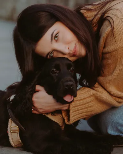 Una ragazza abbraccia Maggie, cagnolina nera
