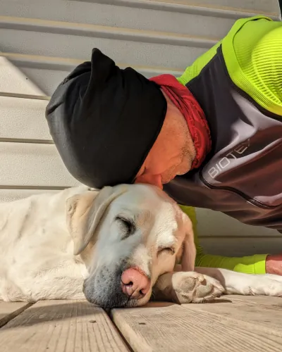 Nicola Inversi abbraccia Erin, cane dal pelo chiaro, sdraiata su un pontile